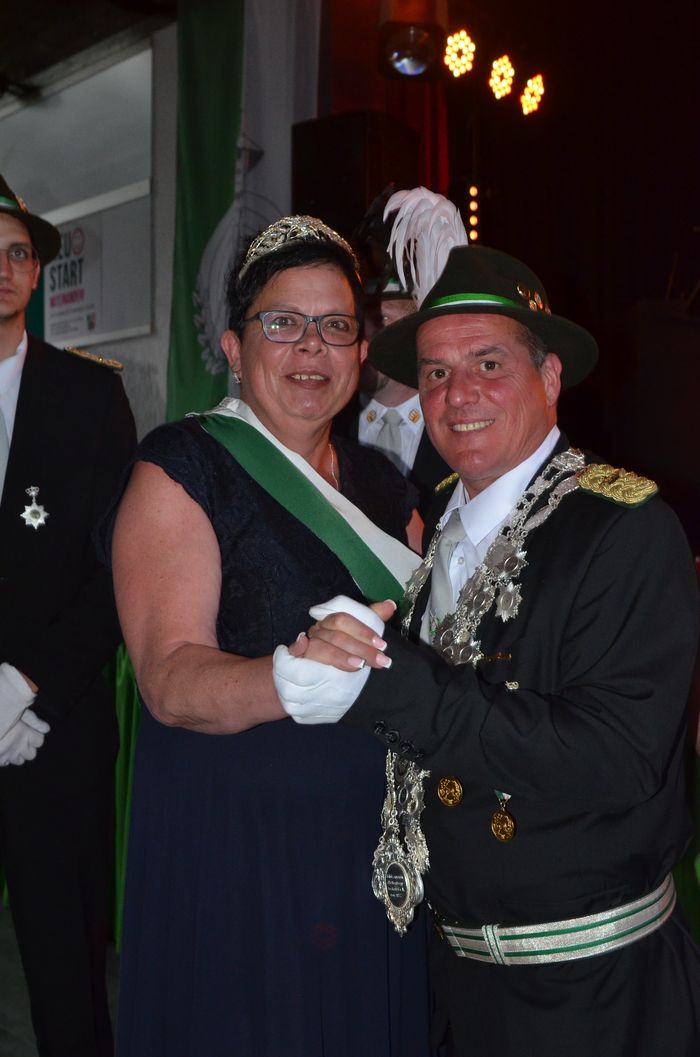 Zwei Männer in historischen Uniformen und ein Mann im Hintergrund mit Orden umarmen sich auf dem Schützenfest Oestertal.